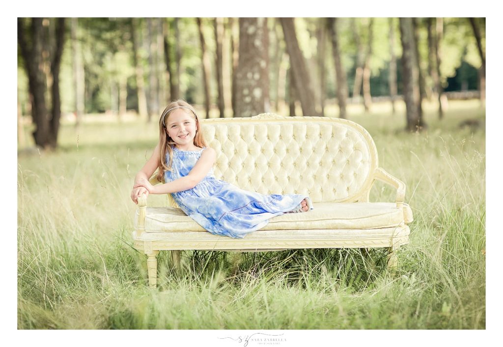 sister sits on couch during family session with Sara Zarrella Photography