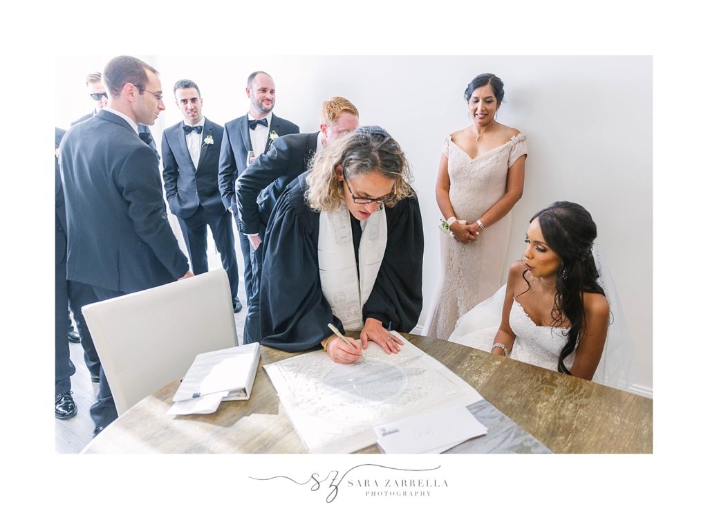 bride and groom sign Ketubah with Rabbi photographed by Sara Zarrella Photography