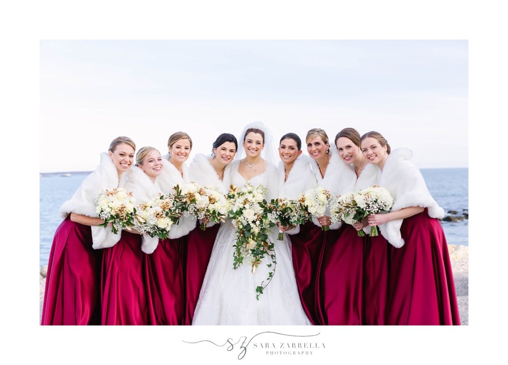 bridesmaids in red gowns with white furs for winter wedding photographed by Sara Zarrella Photography