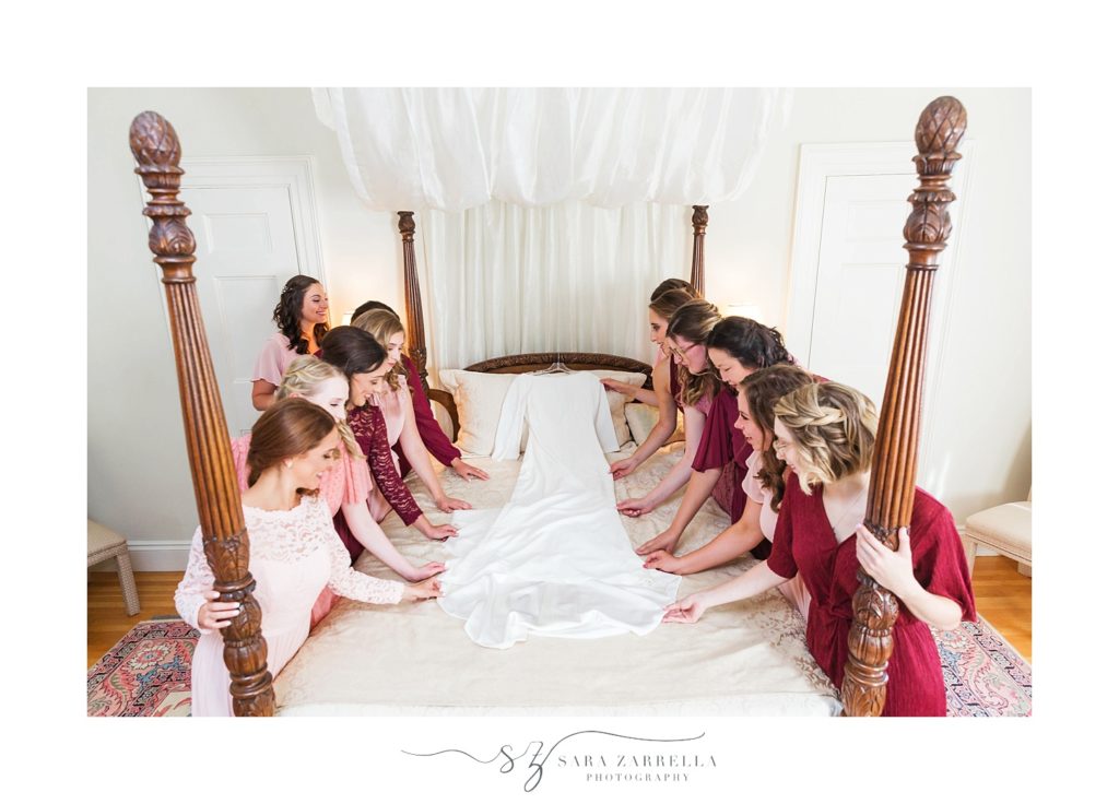 bride and bridesmaids pray over wedding gown photographed by Sara Zarrella Photography