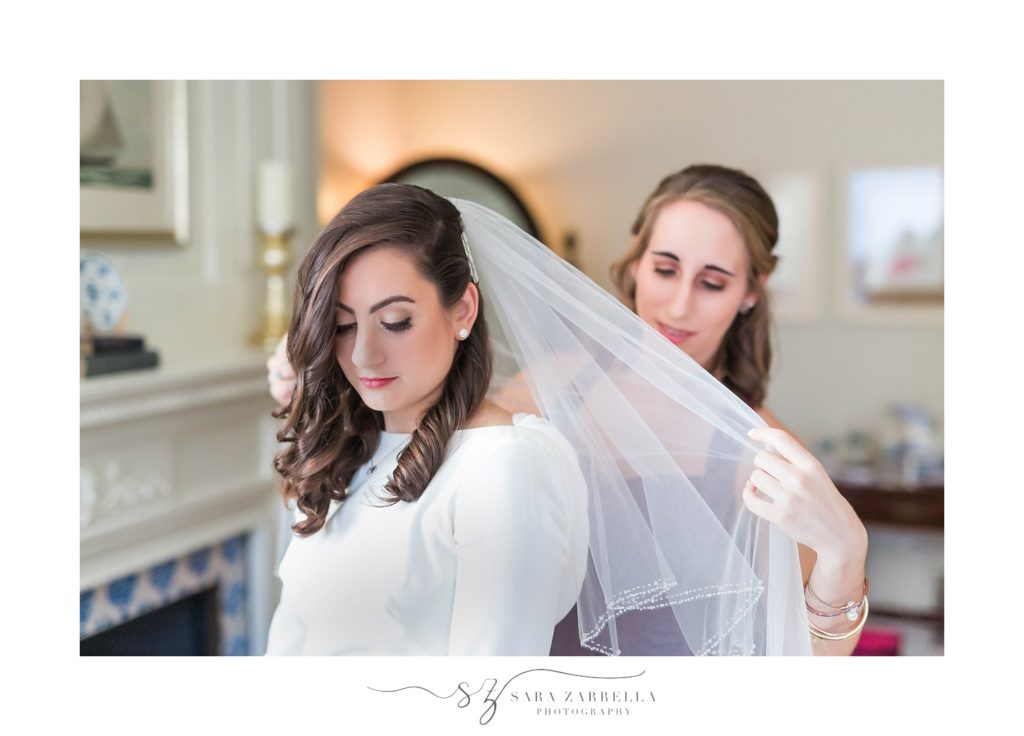 bridesmaid helps bride with veil before MA wedding day photographed by Sara Zarrella Photography