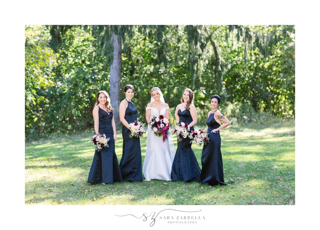 bride and bridesmaids in black gowns pose for Sara Zarrella Photography