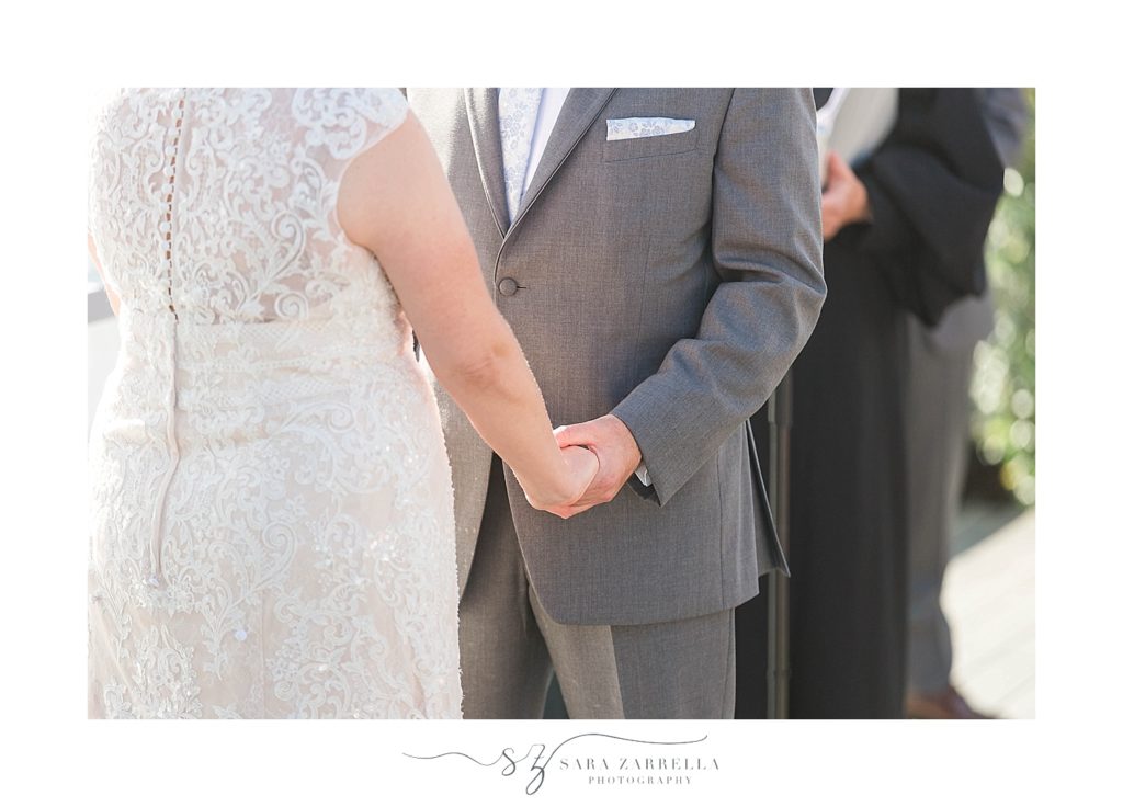 bride and groom hold hands during wedding ceremony photographed by Sara Zarrella Photography