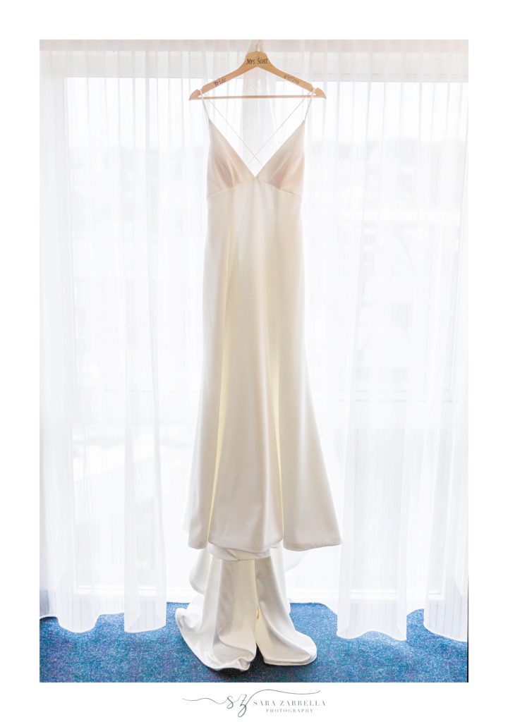 bride's wedding dress hangs in Newport RI window photographed by Sara Zarrella Photography