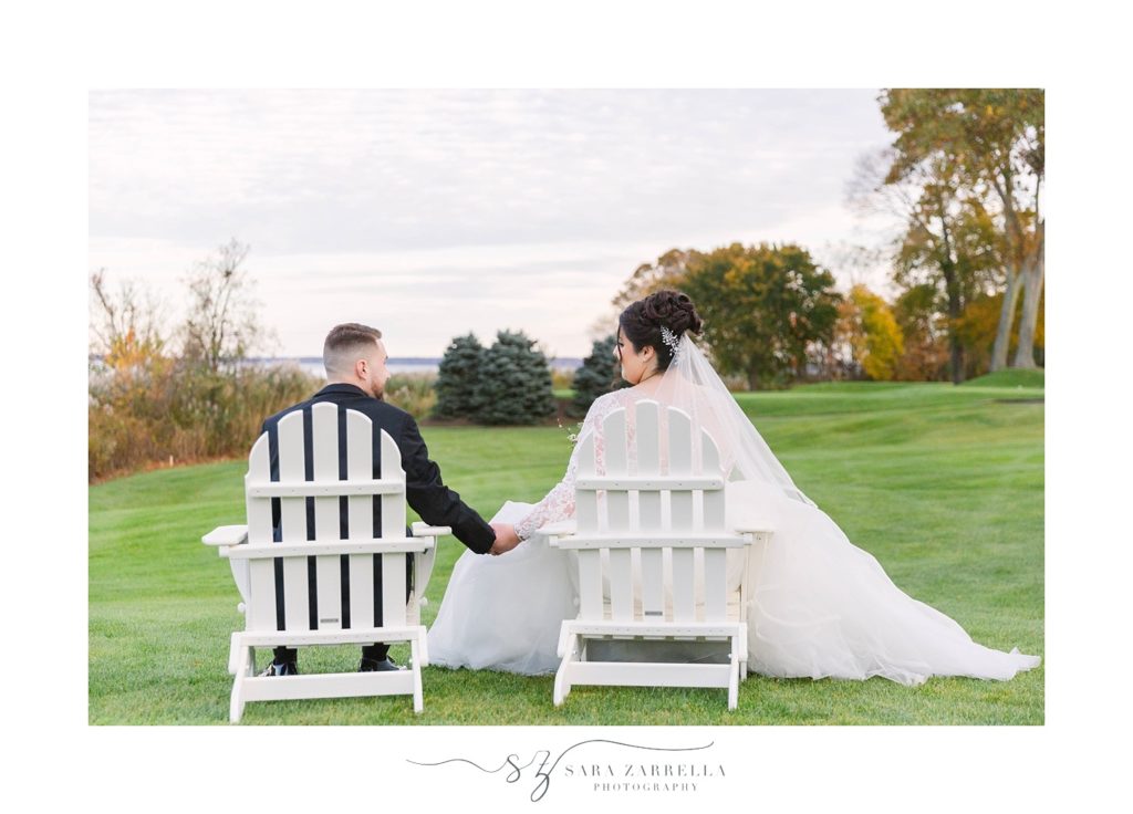bride and groom sit in Adirondack chairs with Sara Zarrella Photography