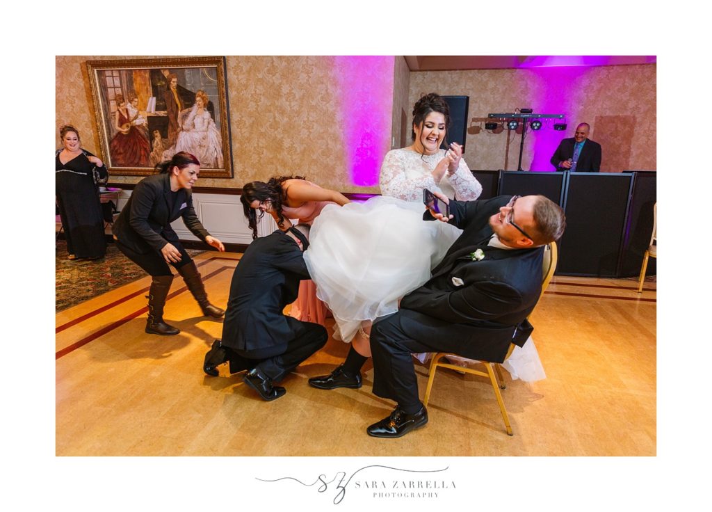 groom tries to find garter photographed by Sara Zarrella Photography