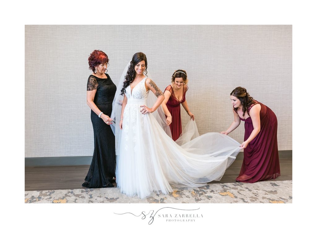 bride gets int wedding dress with bridesmaids photographed by Sara Zarrella Photography