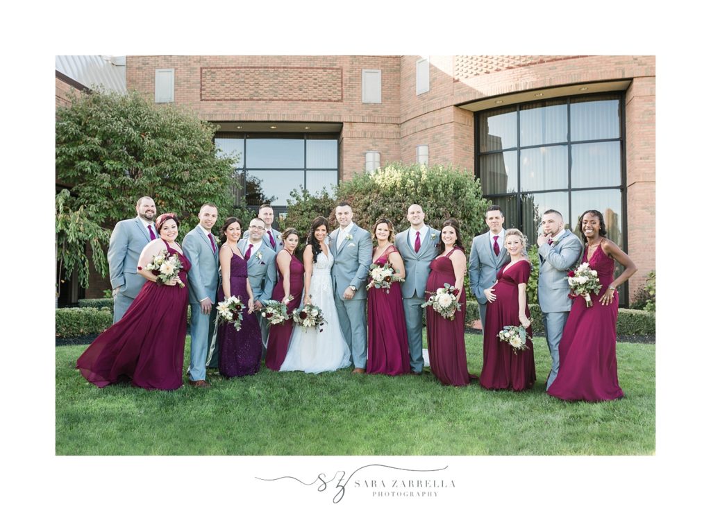 bridal party in grey suits from Carl Anthony and red bridesmaid gowns photographed by Sara Zarrella Photography