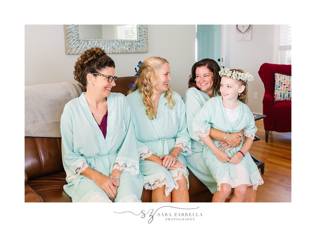 bride sits with bridesmaids and flower girl in teal robes