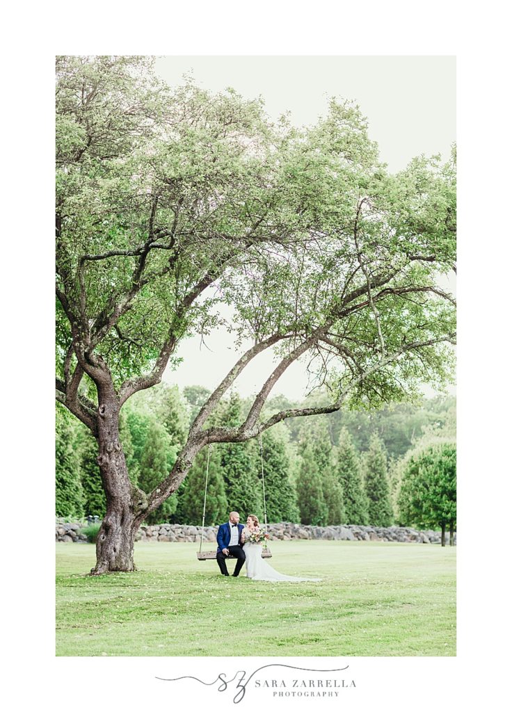 bride and groom sit on swing at Gerald's Farm