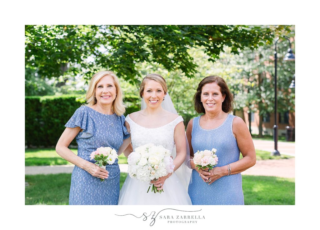 bride poses with mother and mother in law in blue gowns