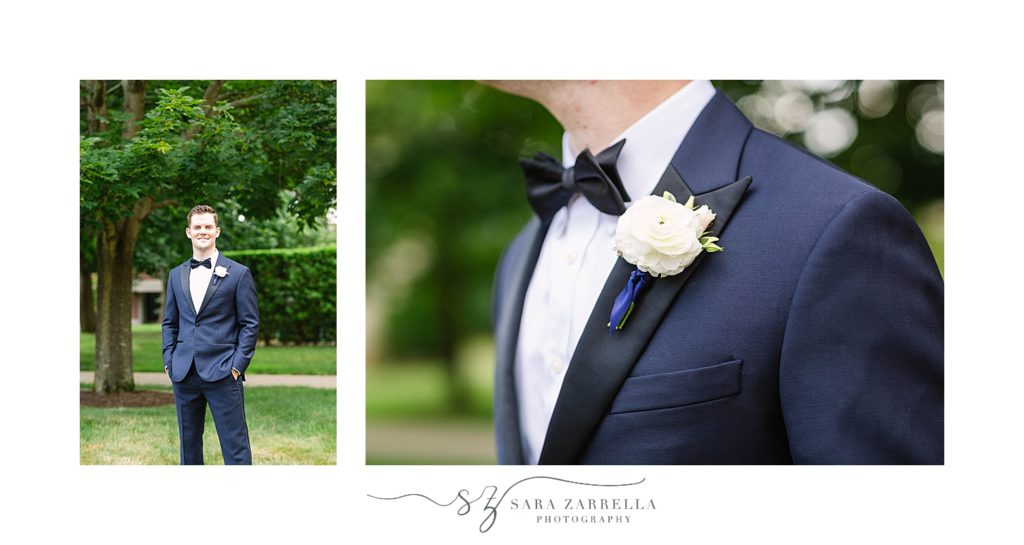 groom poses in navy suit with white boutineere
