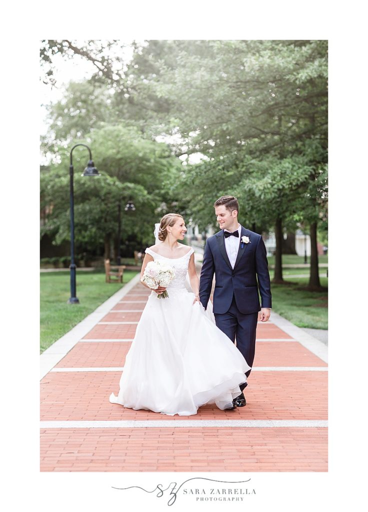 bride and groom walk down sidewalk at Providence College