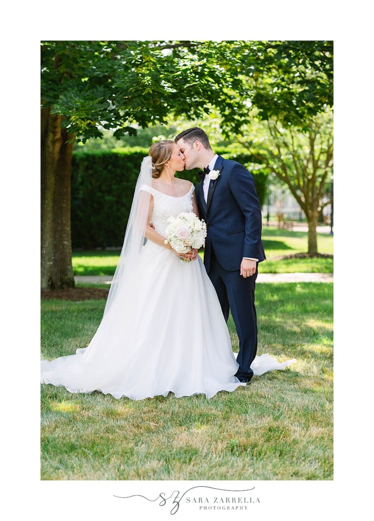 bride and groom kiss under trees at Providence College