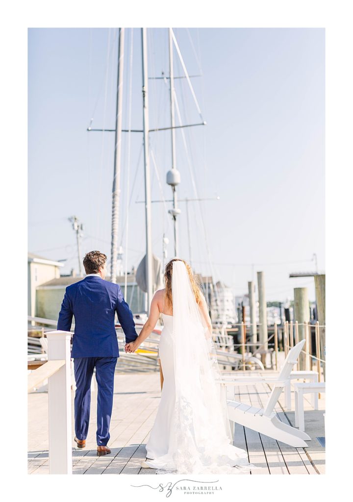 newlyweds hold hands walking through Newport RI marina