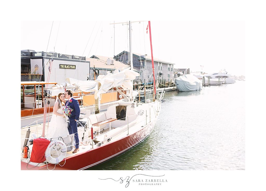 bride and groom pose on sailboat in Newport RI
