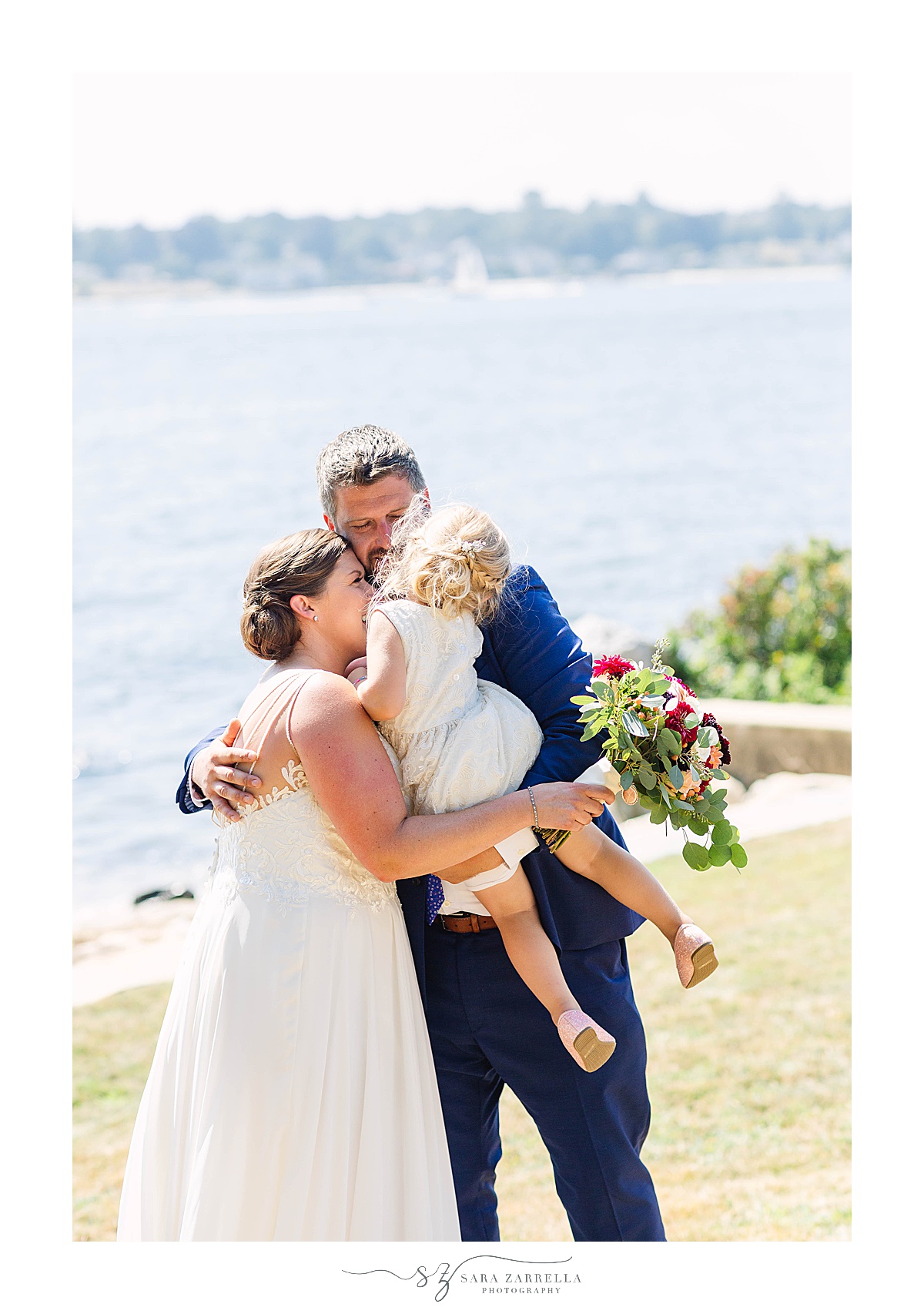 bride and groom pose with daughter on waterfront estate wedding day