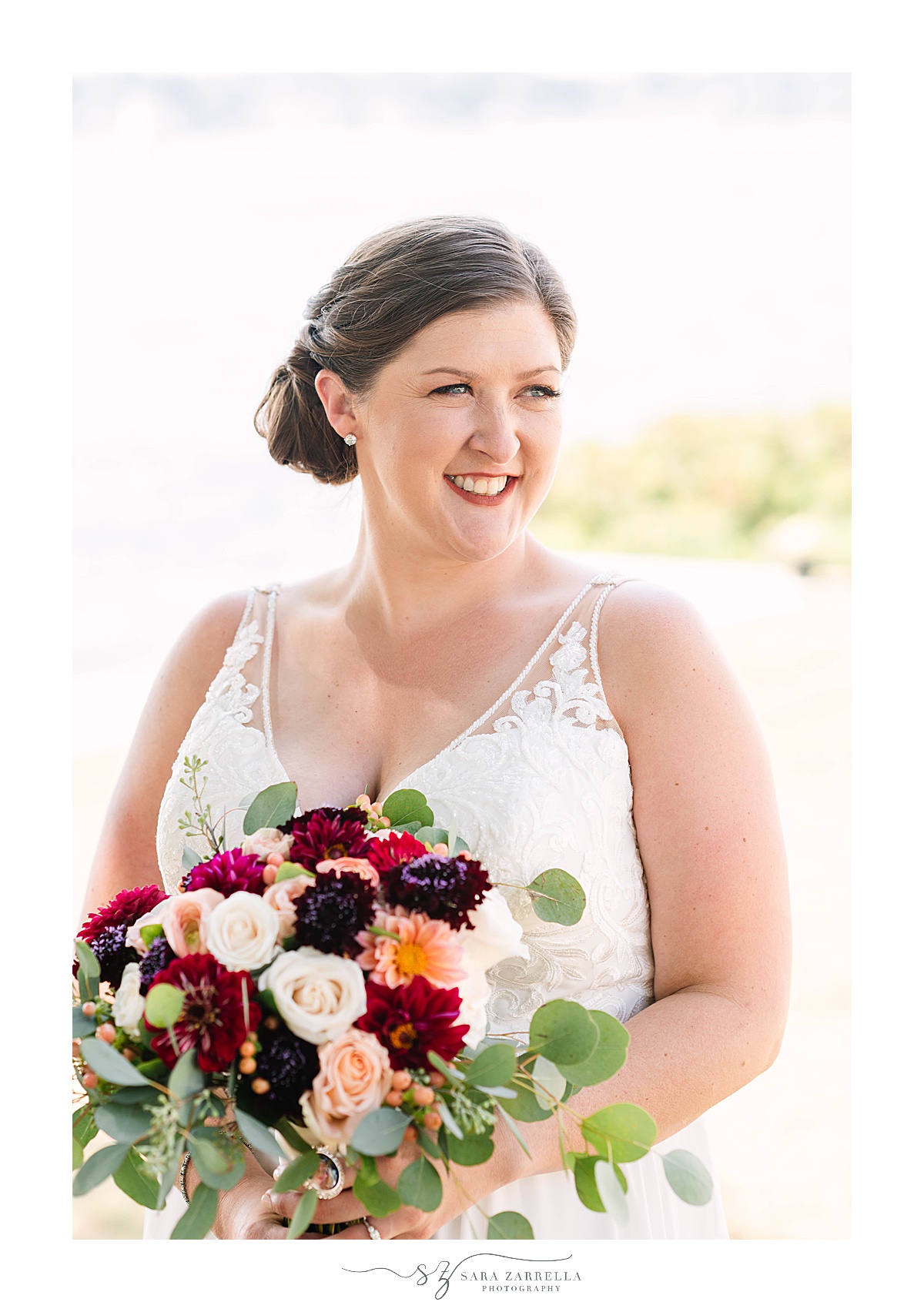 bride holds bouquet with red, pink and green flowers