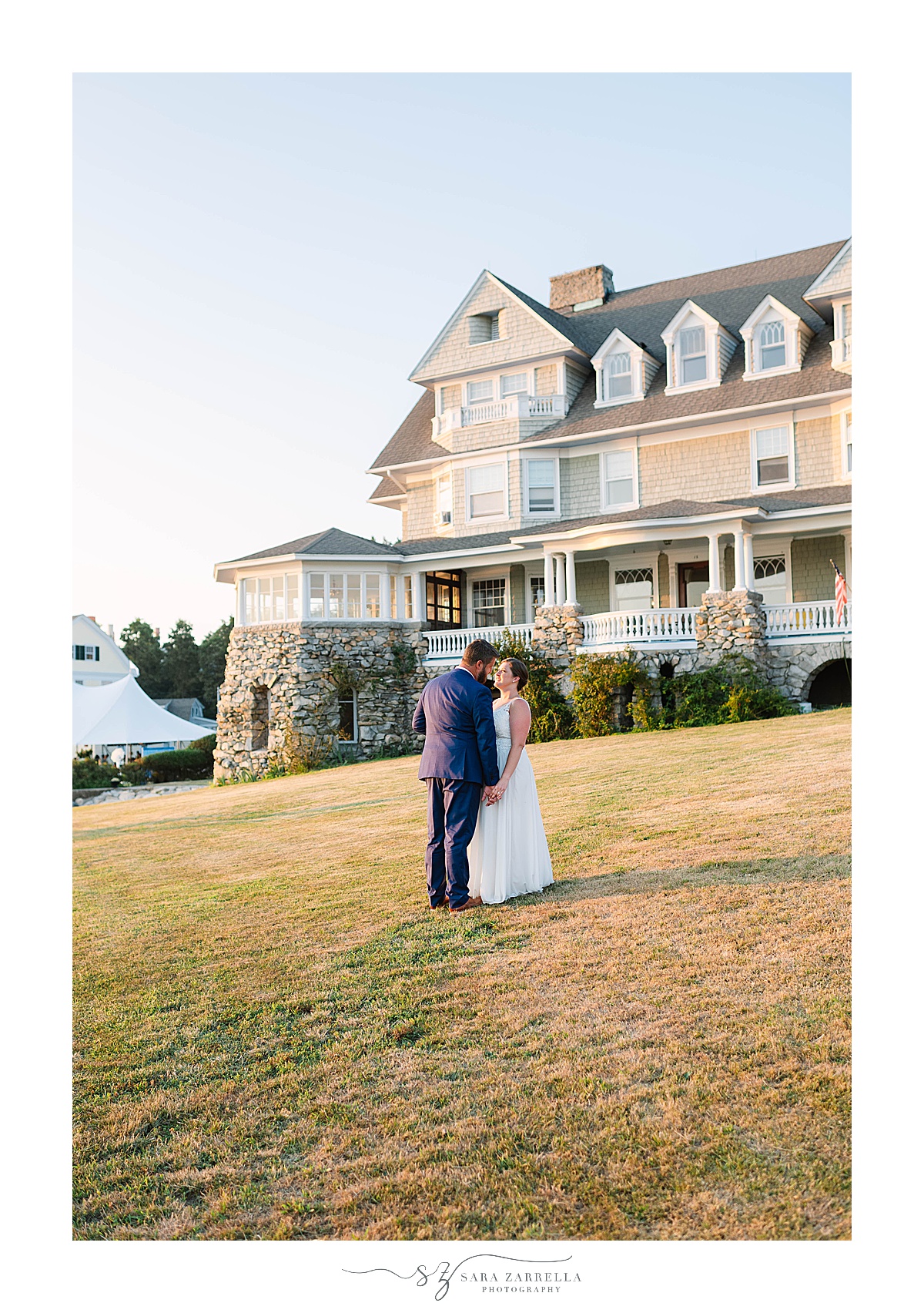 bride and groom walk along lawn during waterfront estate wedding