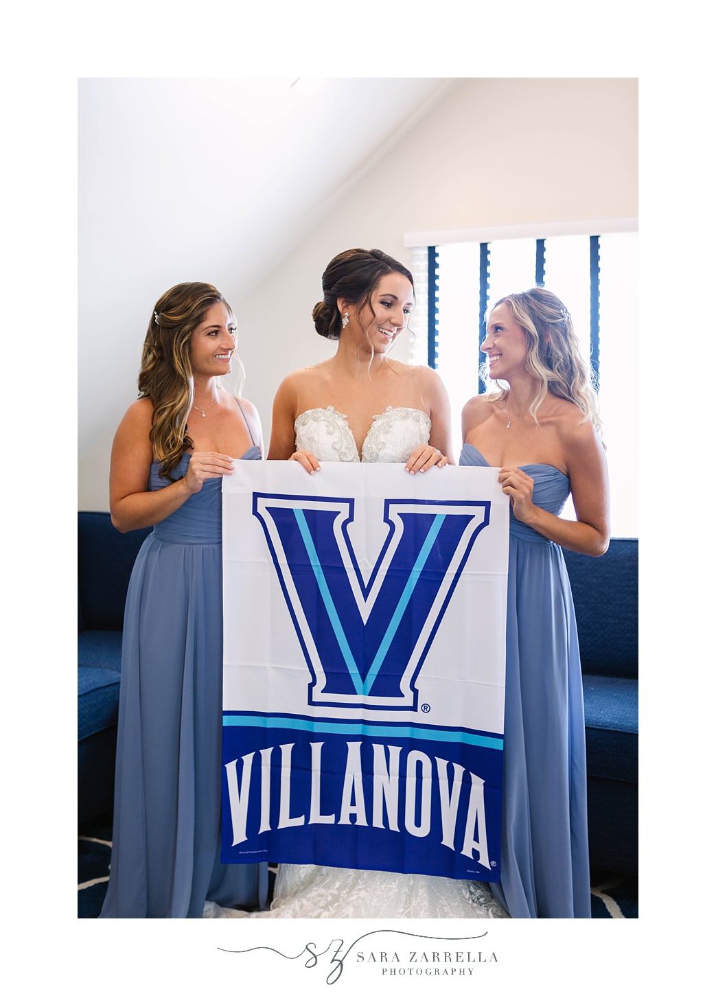 bride and bridesmaids hold Villanva flag during wedding day prep