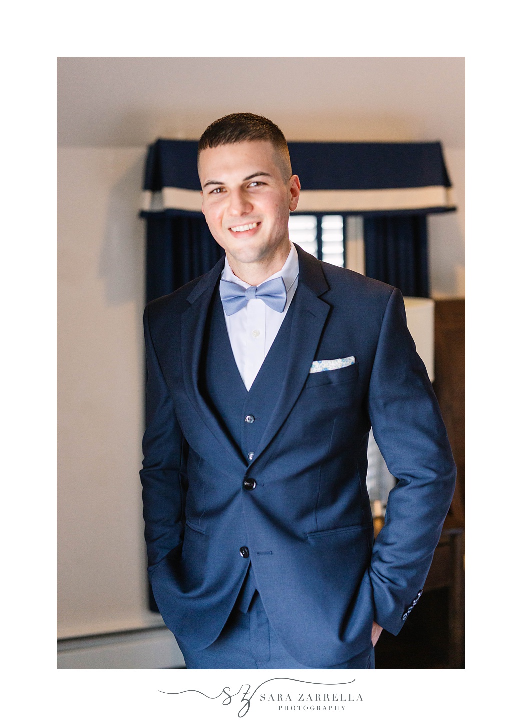 groom in navy suit poses for Sara Zarrella Photography