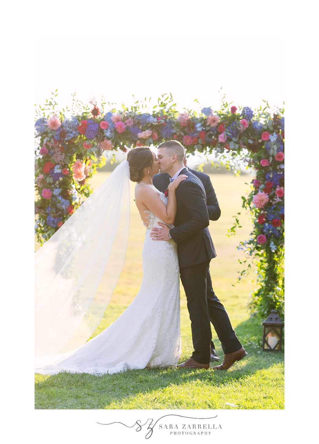 first kiss during Blithewold Mansion Wedding ceremony under floral arbor