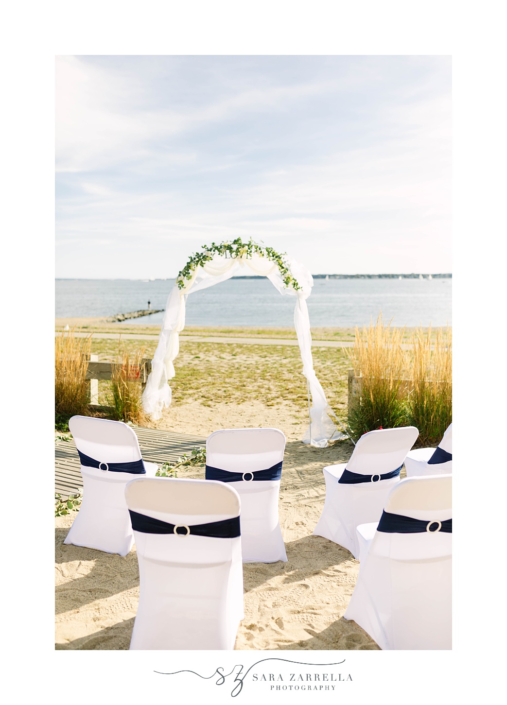 beachfront wedding ceremony with arbor and seats with navy accents