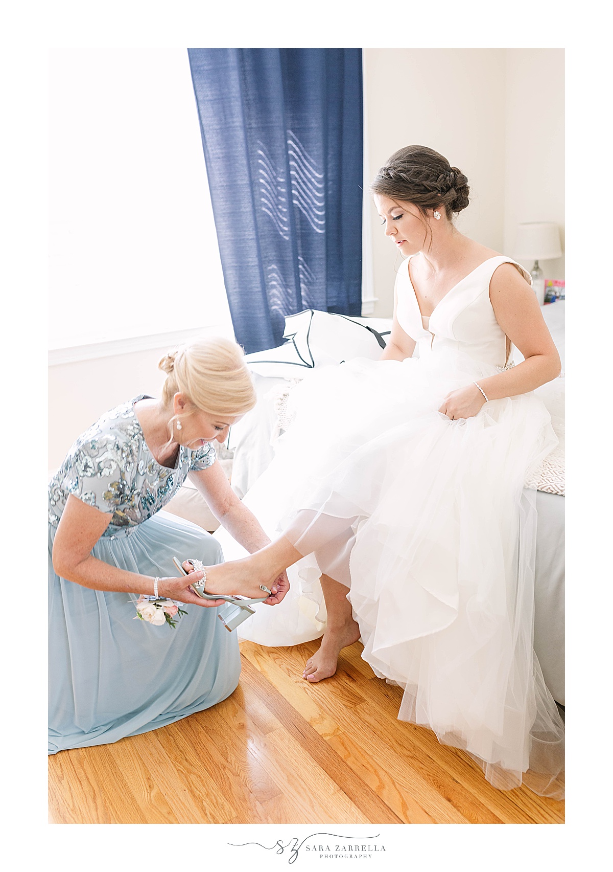 mom puts shoe on bride before RI wedding day