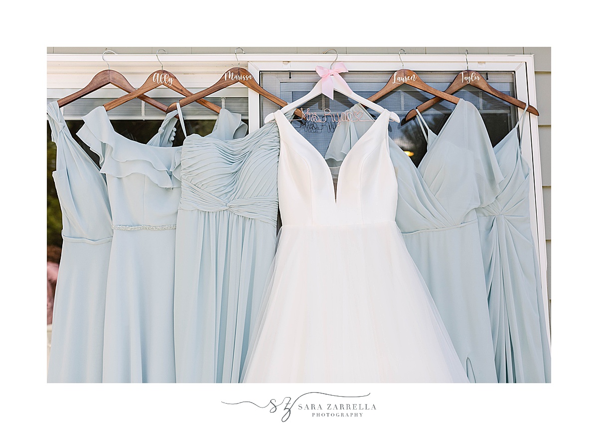bride's dress hangs with pale blue bridesmaid gowns in Rhode Island