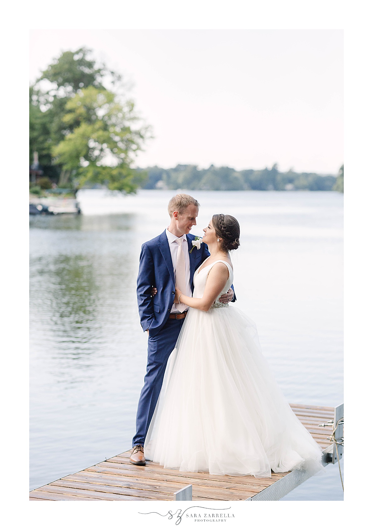 bride and groom stand on pier