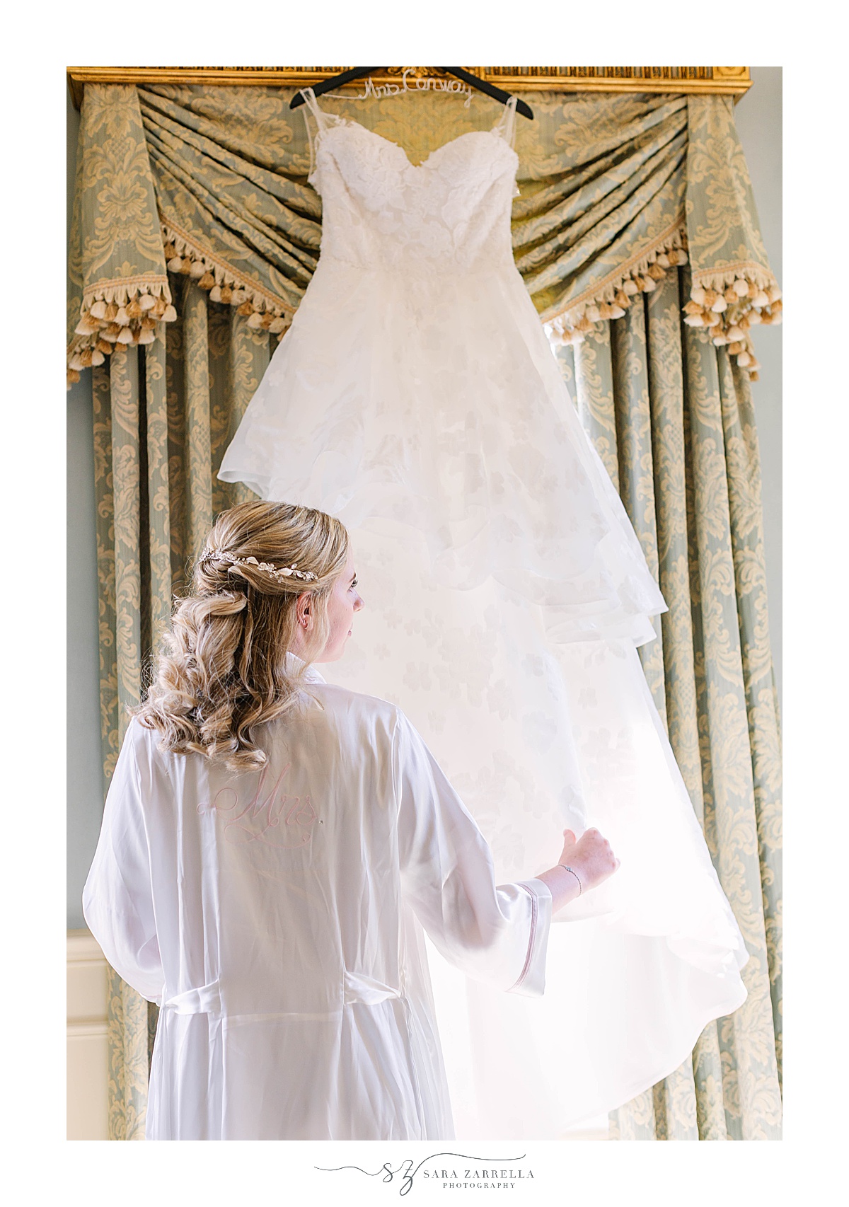 bride looks at wedding dress hanging in bridal suite at The Chanler at Cliff Walk