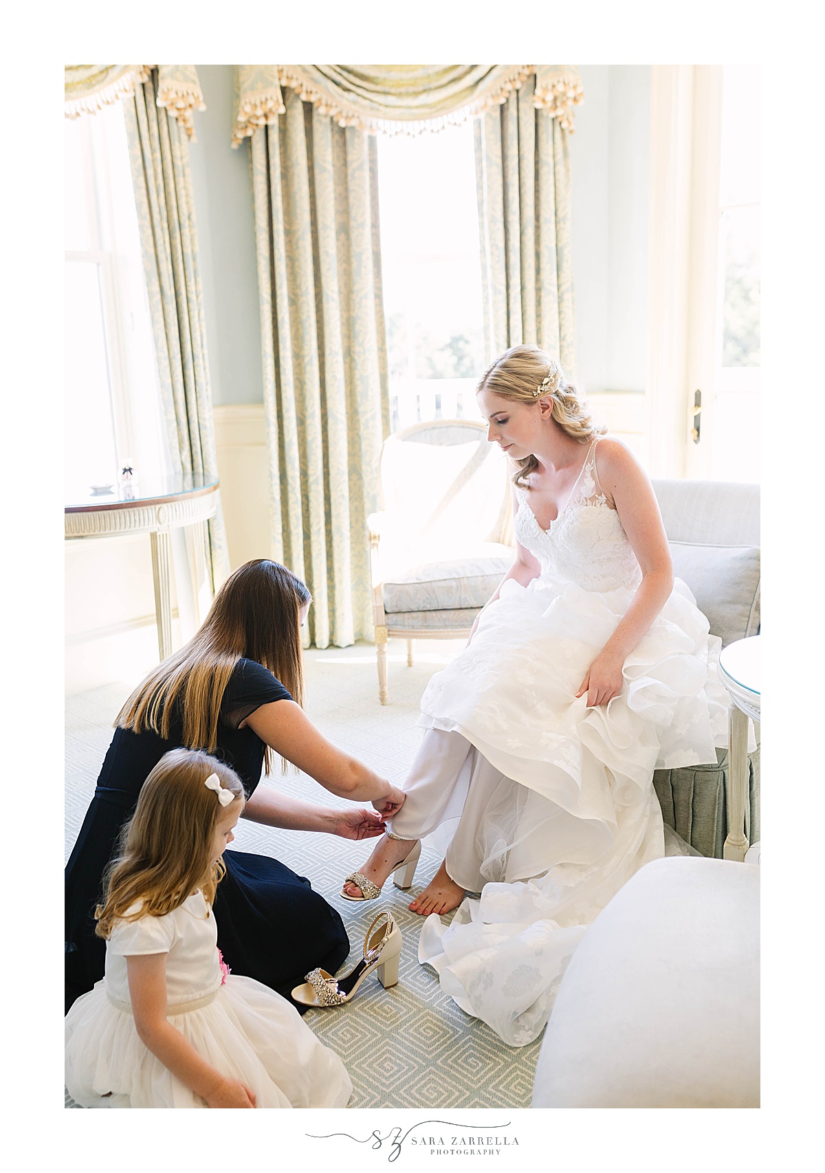 bridesmaid helps bride with shoes on wedding day