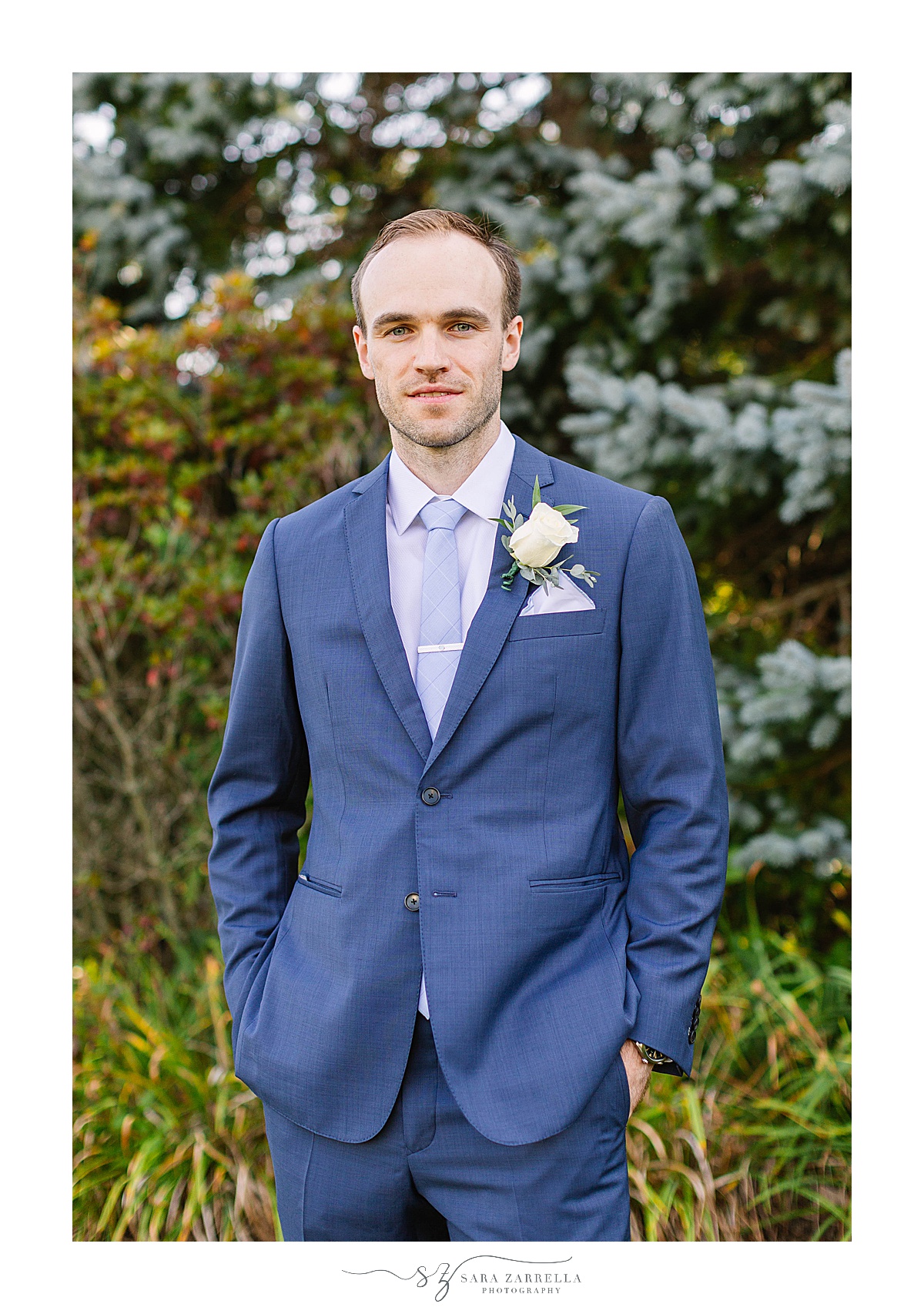groom in navy suit poses after RI wedding