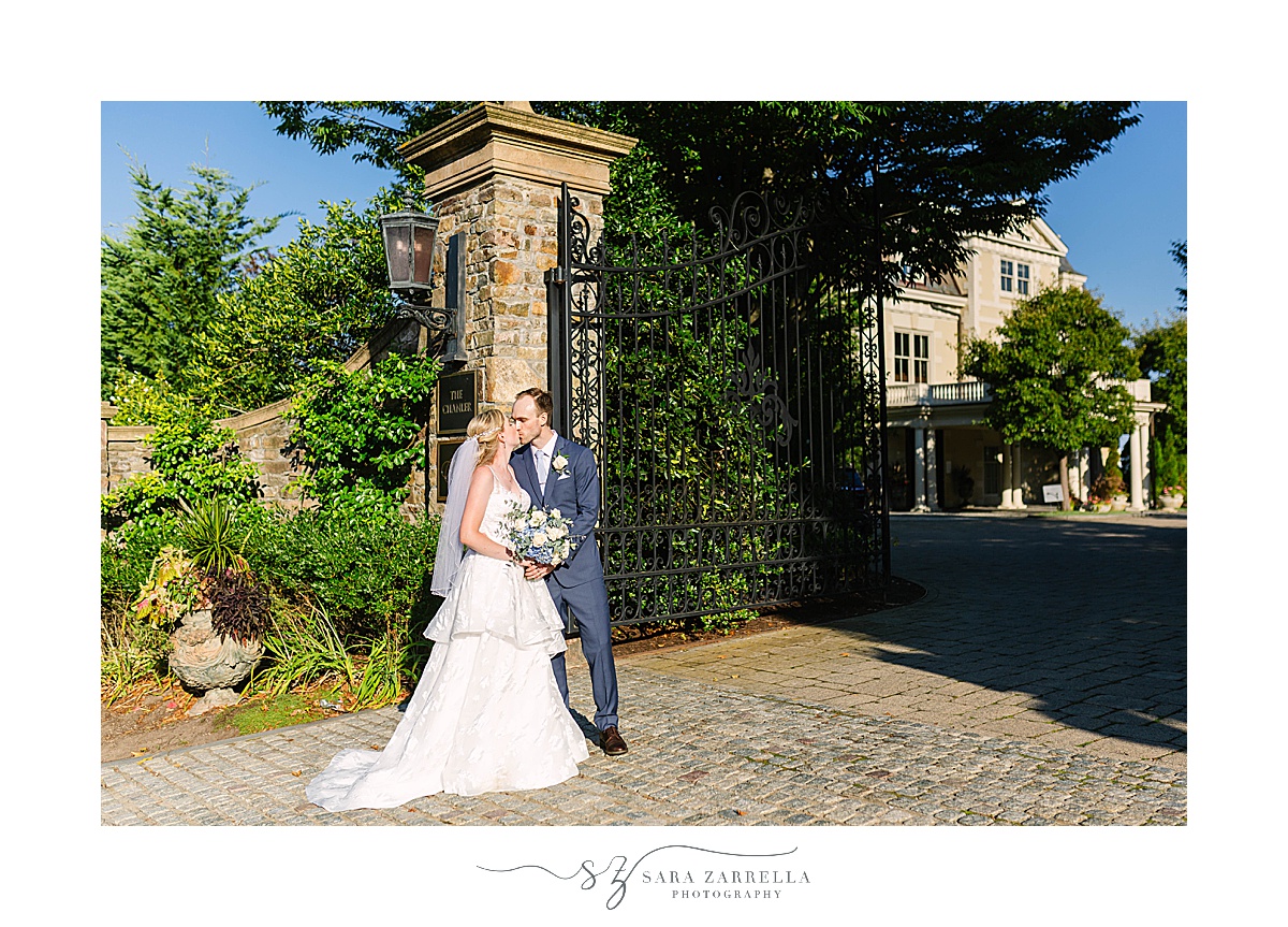 newlyweds kiss at iron gate of The Chanler at Cliff Walk