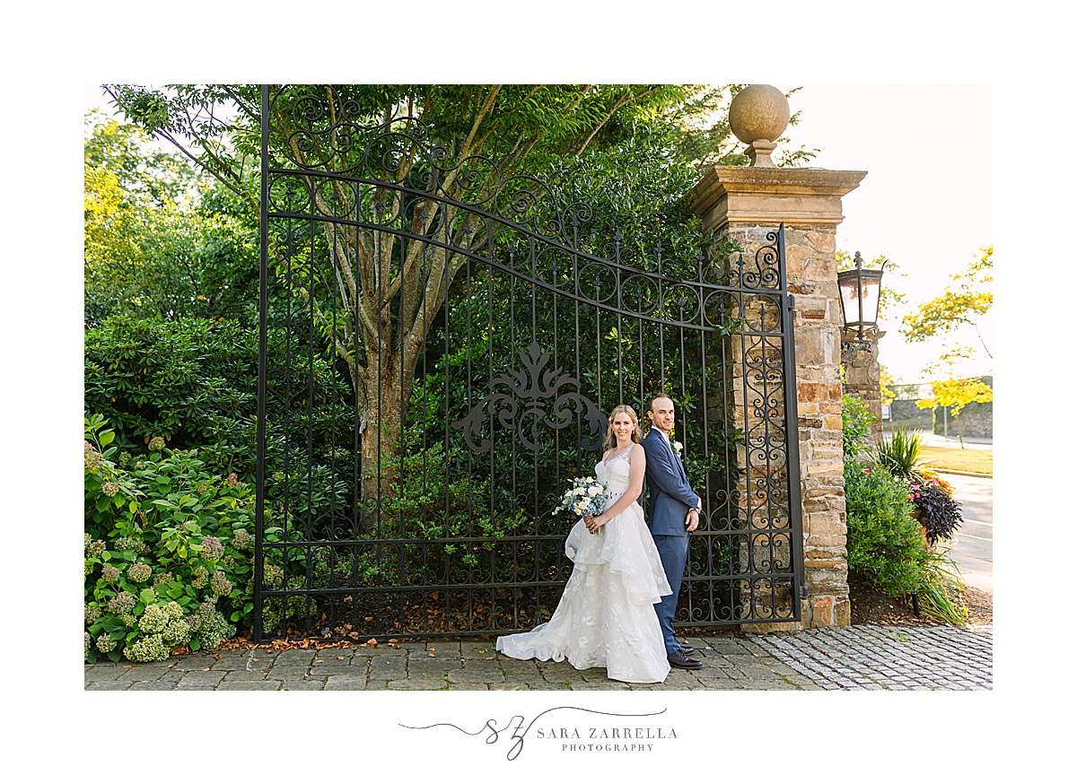 newlyweds pose by gate at The Chanler at Cliff Walk