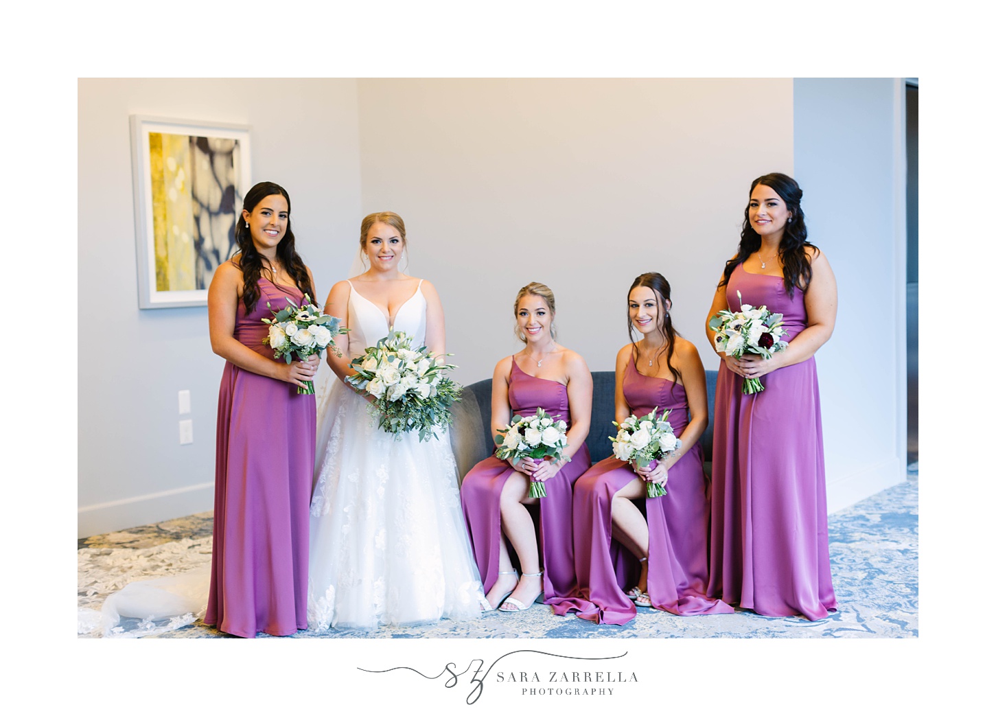 bride and bridesmaids in purple gowns pose in lobby of Rhode Island venue 