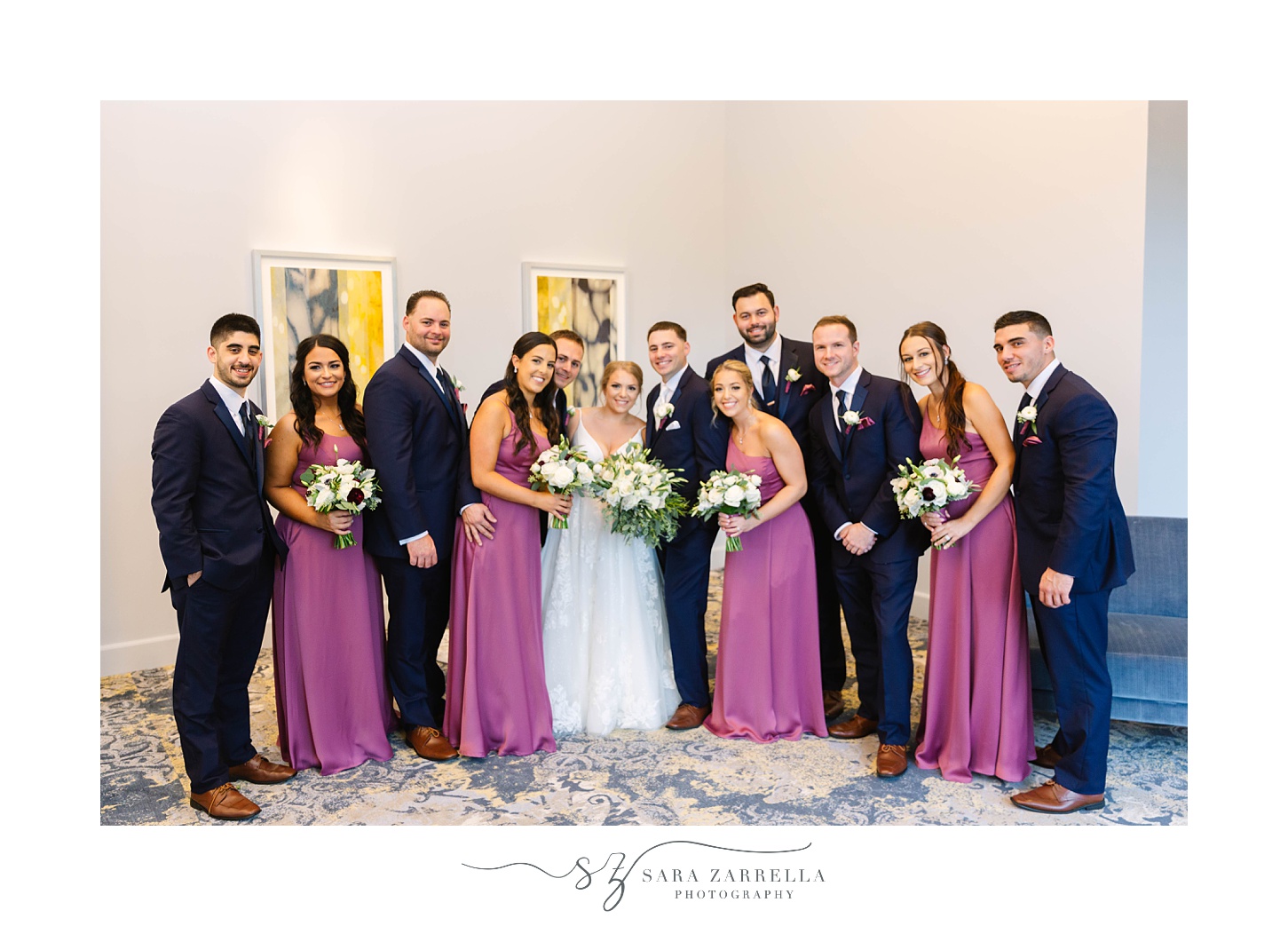 bridesmaids in purple gowns pose with bride and groom