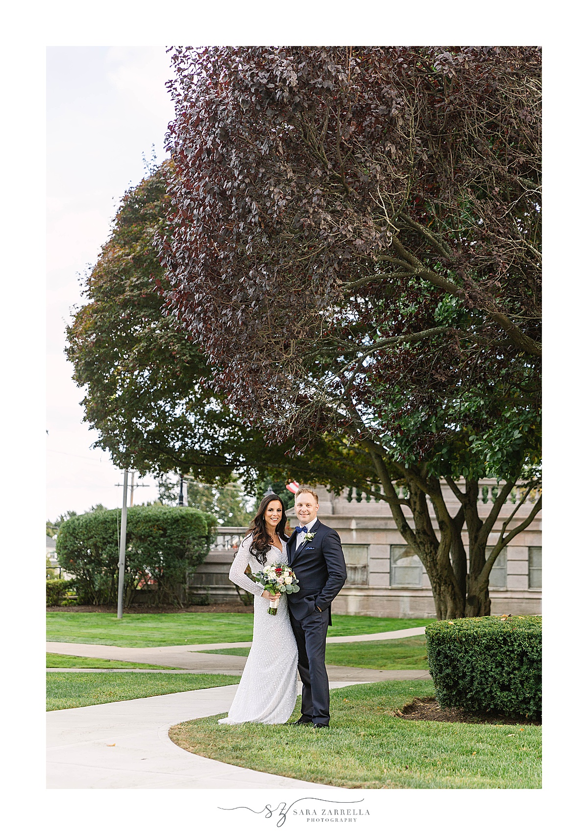 bride and groom pose by tree in Rhode Island