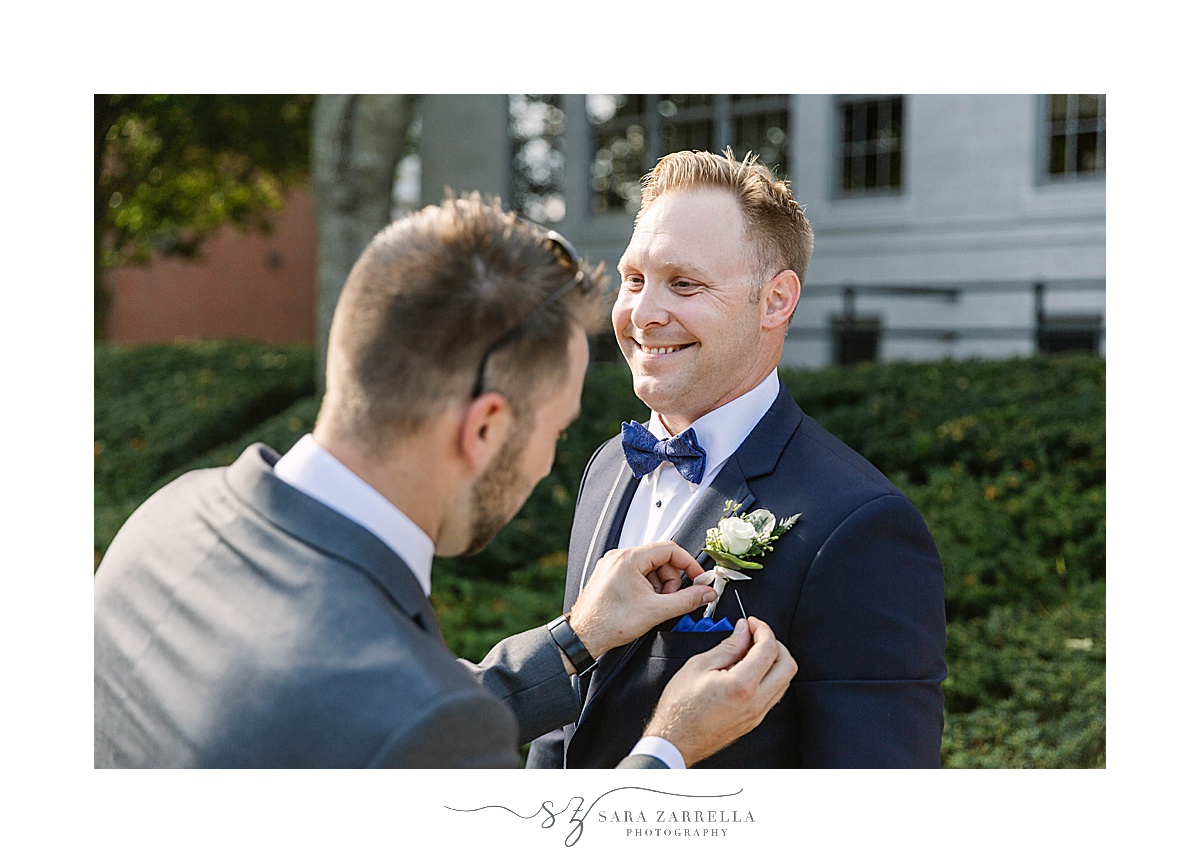 groom's boutonnière adjusted before wedding ceremony