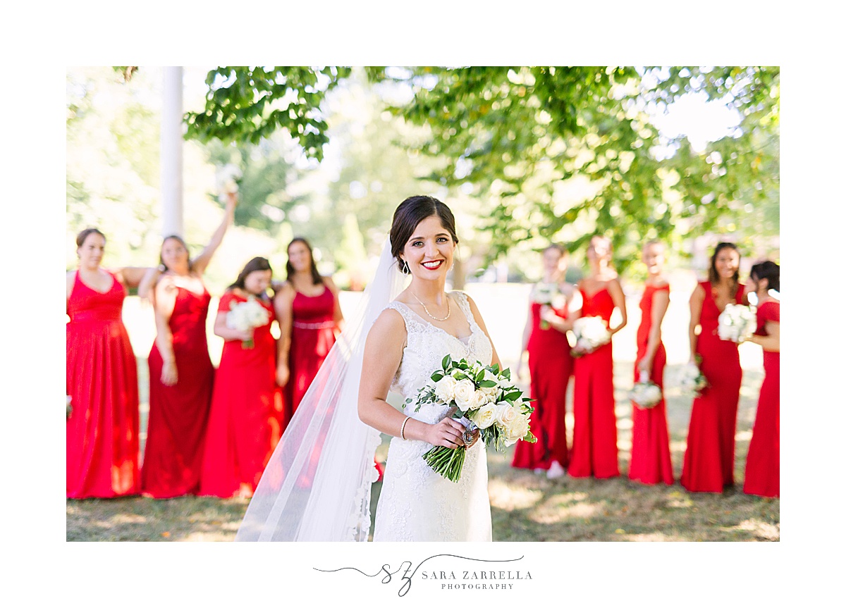 bride stands in front of bridesmaids in red gowns