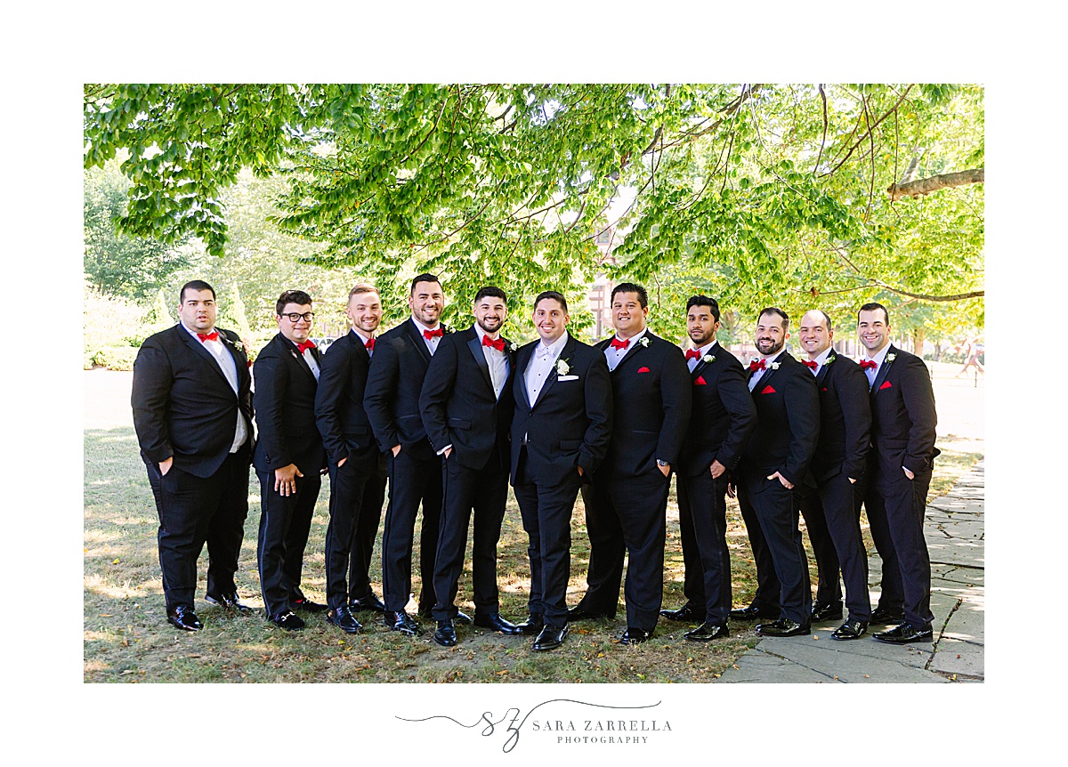 groomsmen in black tuxes pose in Newport RI