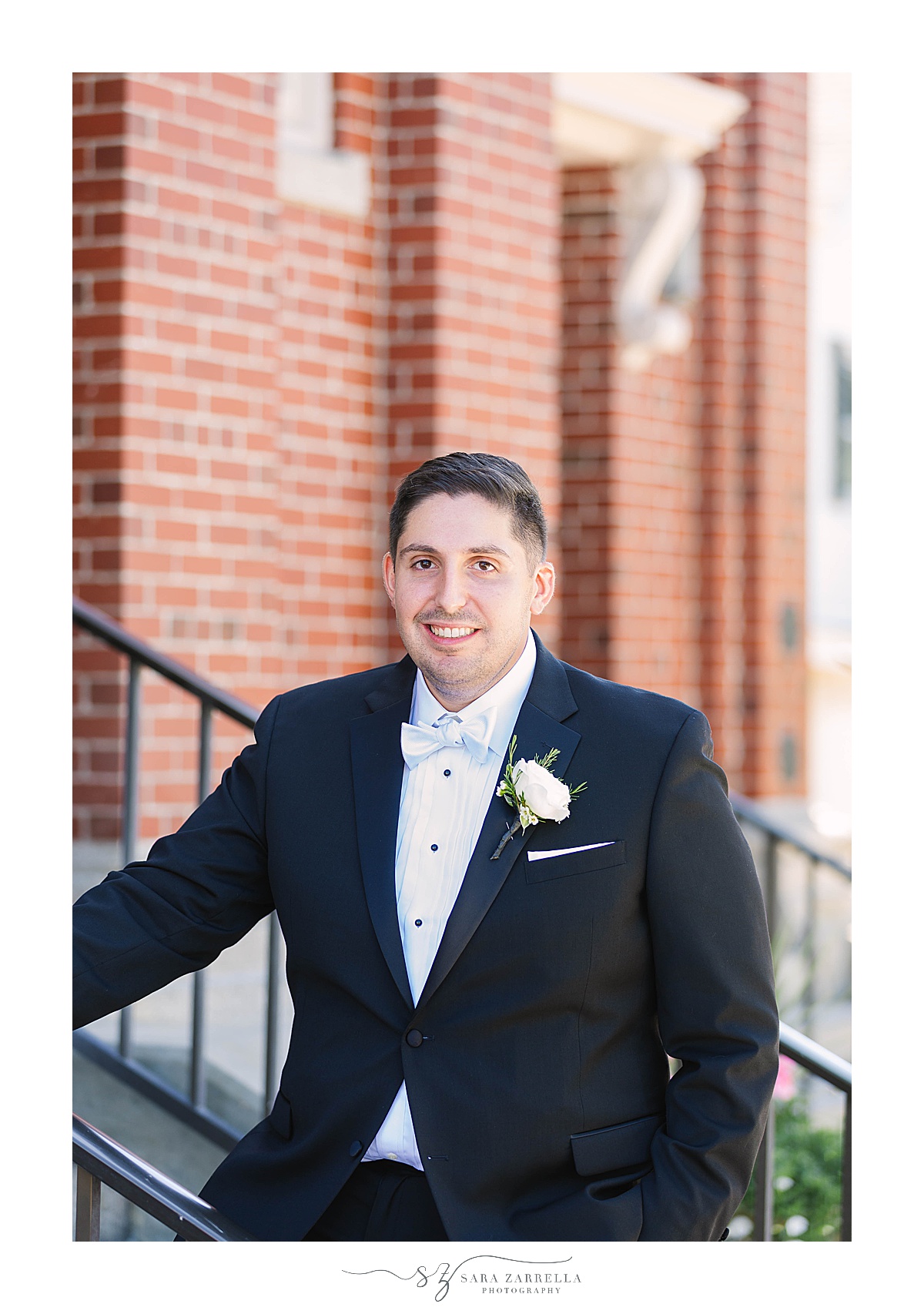 groom in classic tux poses outside church in Rhode Island