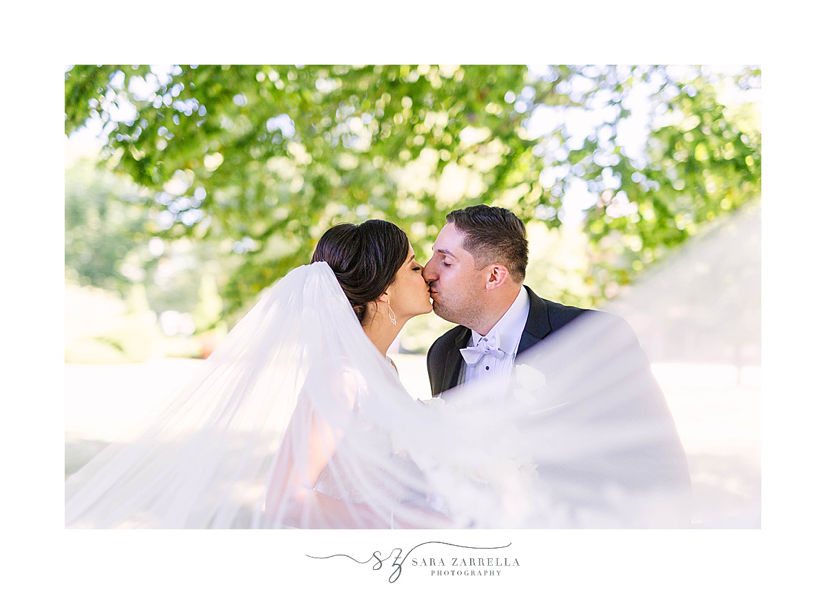 newlyweds kiss while veil floats around them