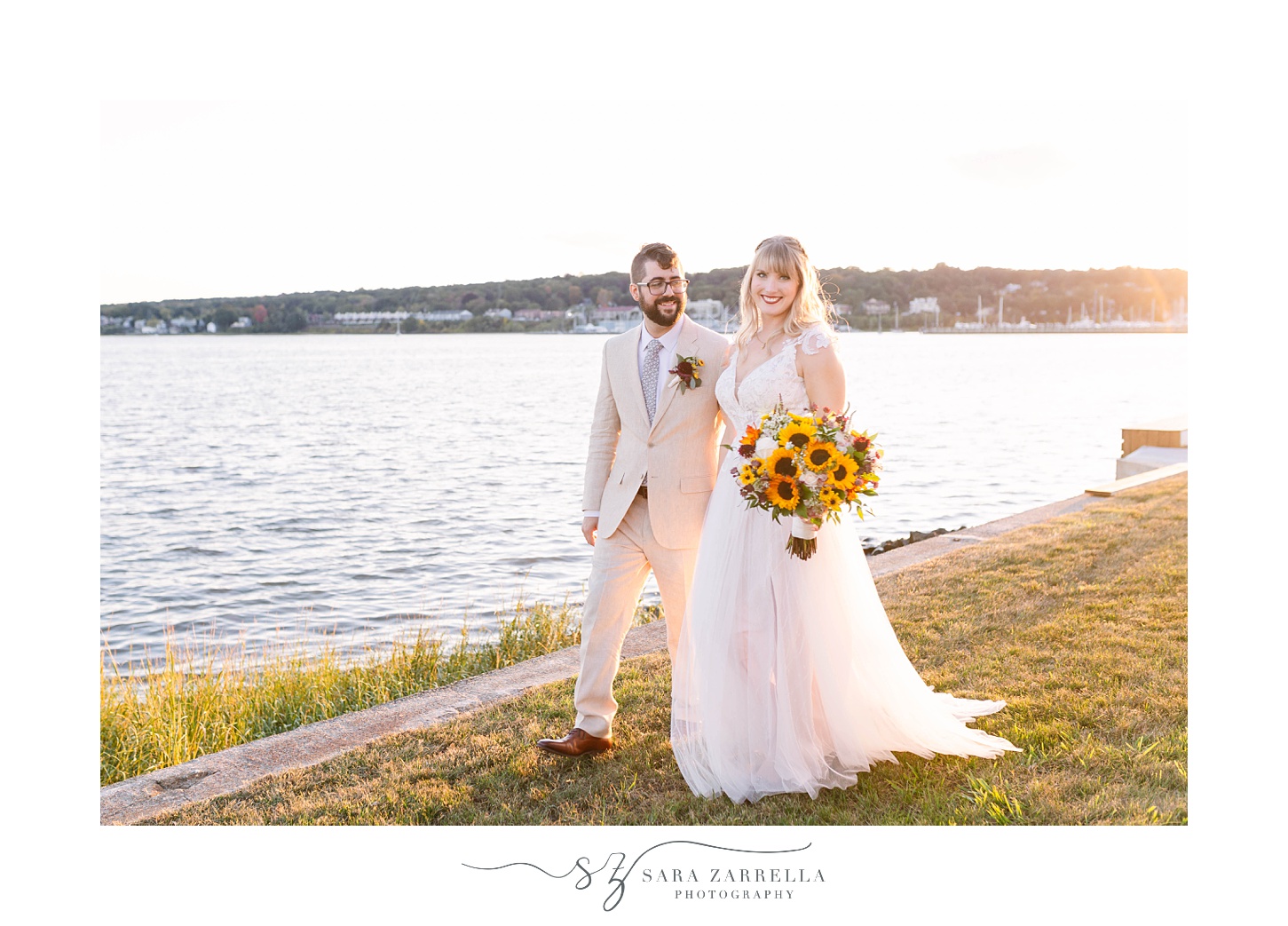 bride and groom walk along water in Rhode Island