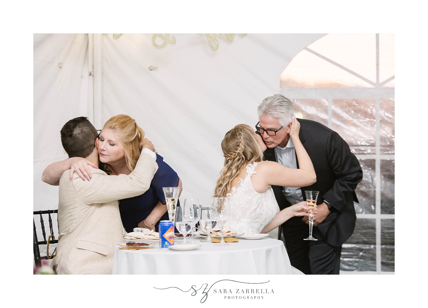 parents hug bride and groom during wedding reception