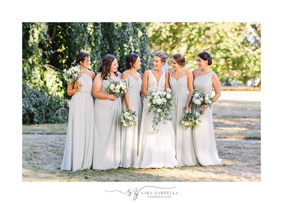 bridesmaids in light grey gowns pose with bride at Blithewold Mansion