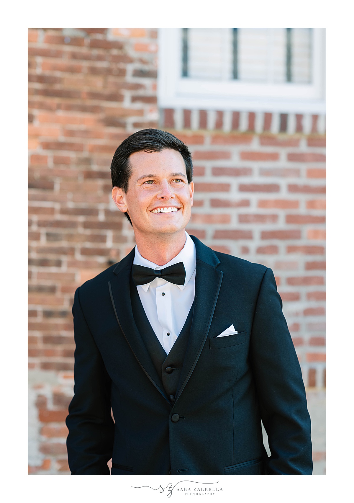 groom in classic tux poses outside Blithewold Mansion