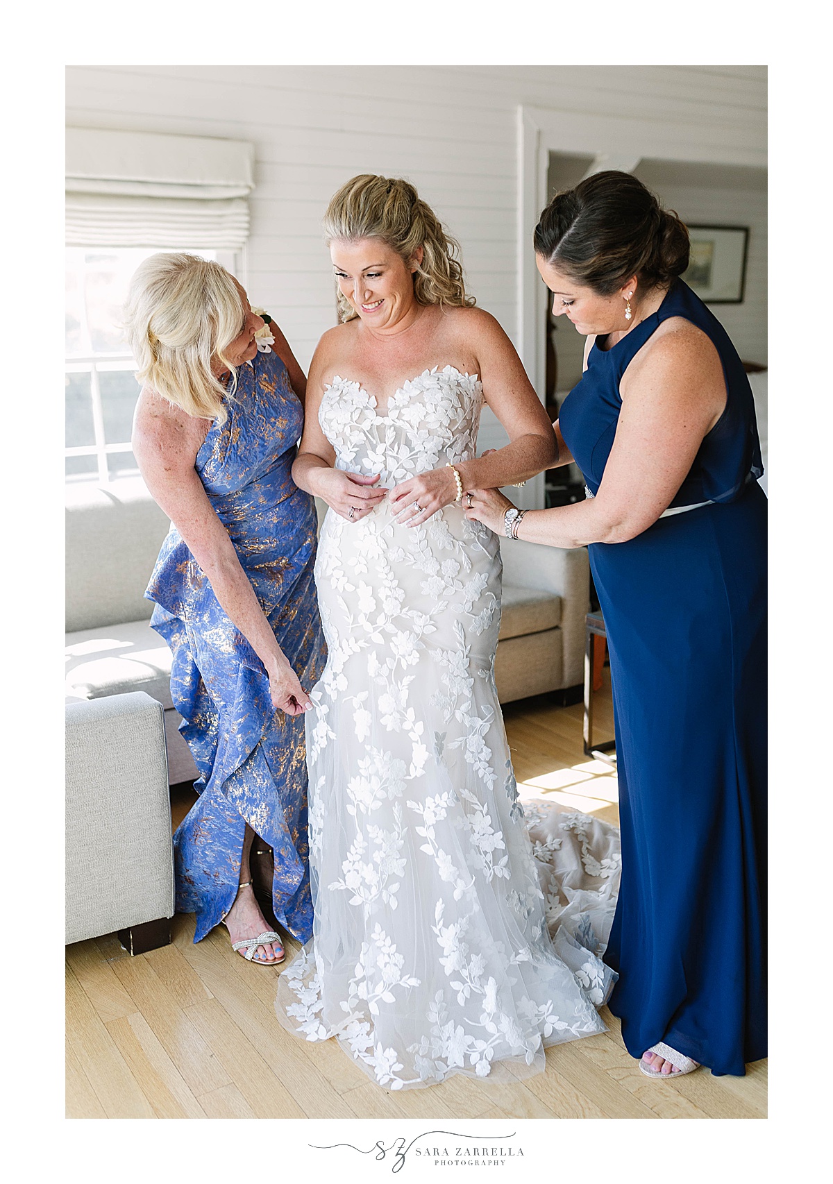 mother of the bride and bridesmaid help bride with gown