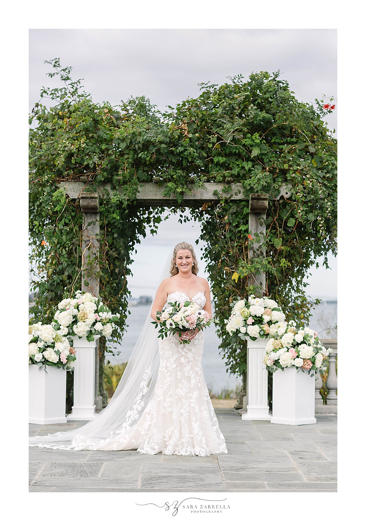 bride poses by arbor at Castle Hill Inn