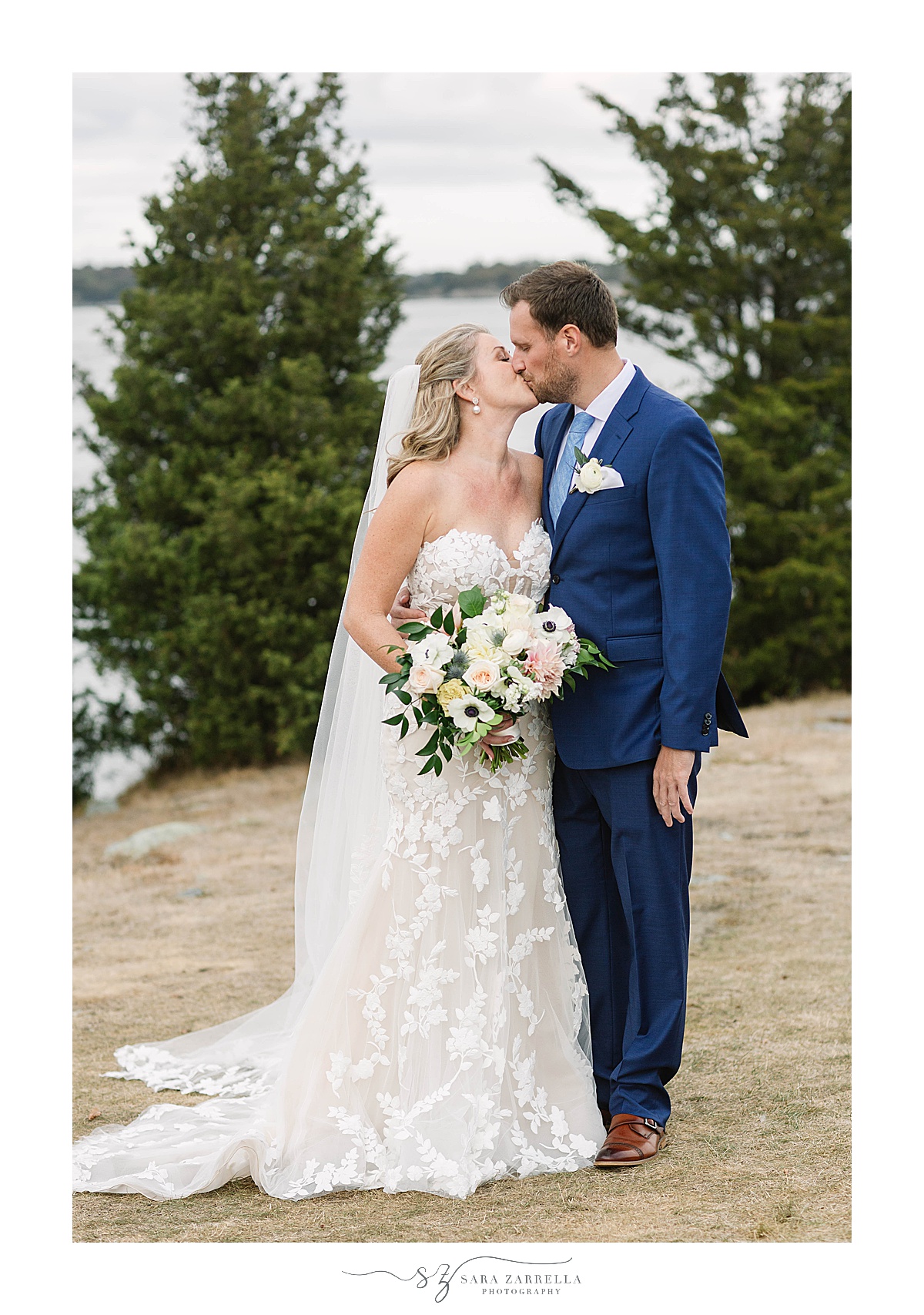 bride and groom kiss along waterfront at Castle Hill Inn